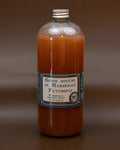 A clear plastic bottle containing orange liquid soap, labeled 'Savon bouche de Marseille Patchouli' with additional text indicating the size and fragrance.