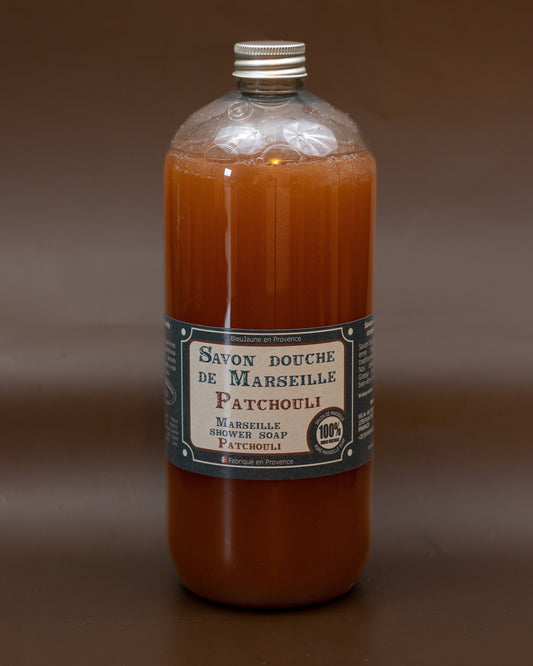 A clear plastic bottle containing orange liquid soap, labeled 'Savon bouche de Marseille Patchouli' with additional text indicating the size and fragrance.