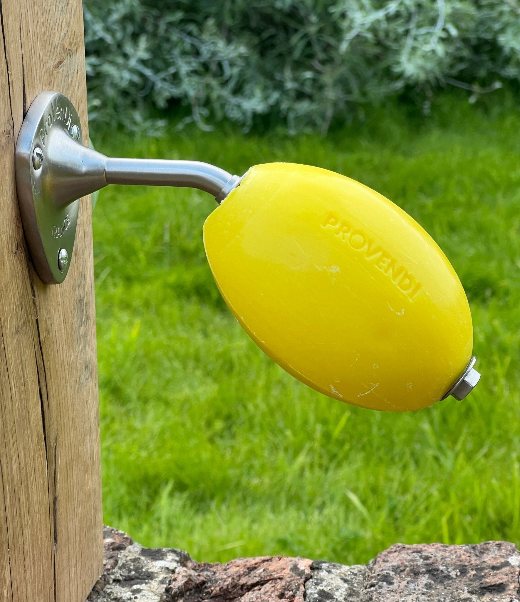 Yellow lemon-shaped object attached to a wooden post with a grassy background