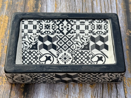 Decorative box with black and white geometric pattern on a wooden surface