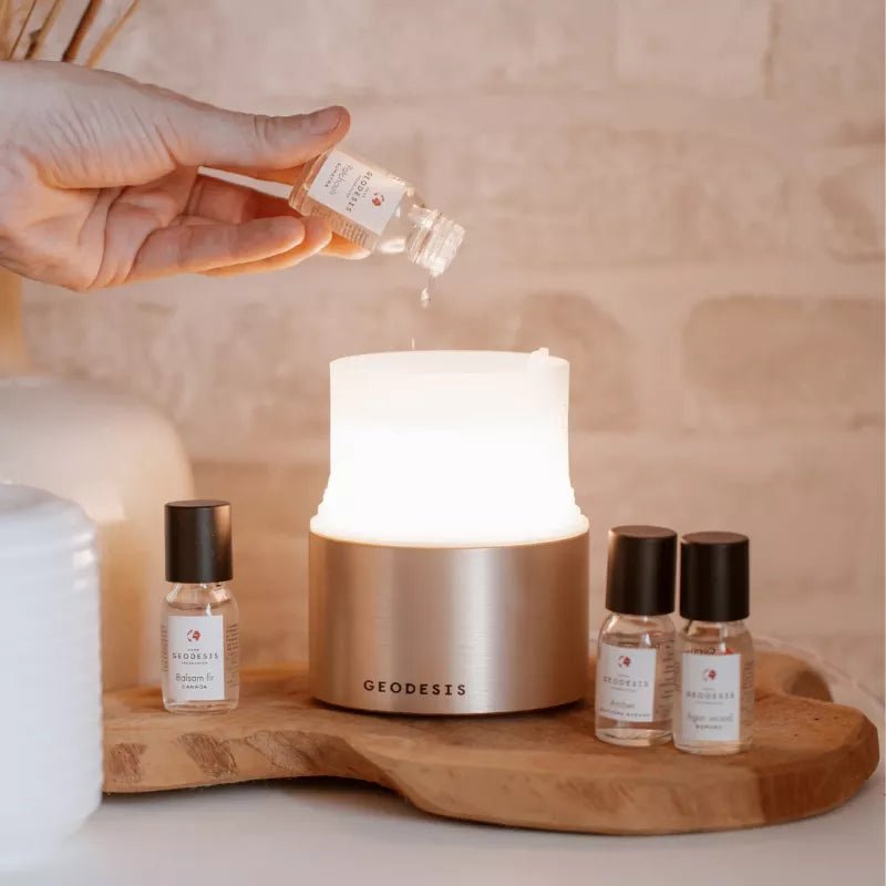 Hand pouring fragrance concentrate oil into a GEODESIS electric atomiser diffuser 